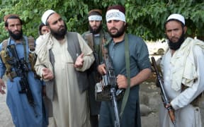 Afghan Taliban militants stand with residents as they took to the street to celebrate ceasefire on the second day of Eid in the outskirts of Jalalabad on June 16,2018. - AFP)