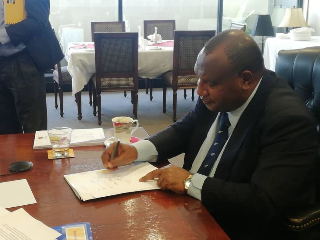 PNG Prime Minister James Marape signs the Statement of Partnership between his country and New Zealand, together with NZ Prime Minister Jacinda Ardern (who he met in a virtual conference) on 14 July, 2021