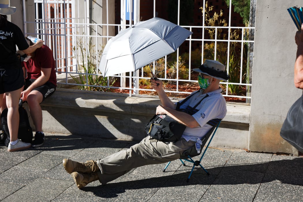 A man shields himself from the sun as he waits in line to be tested for Covid-19 at Royal Perth Hospital in Perth.