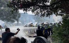 Police using hoses on the fire from behind riot shields.