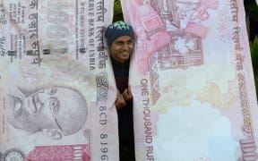 A man poses with replica prints of the demonetised 500 and 1000 rupee notes as part of a street art exhibition in Mumbai November 20, 2016.