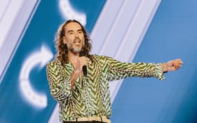English comedian and actor Russell Brand speaks during Turning Point's annual AmericaFest conference, in remembrance of late right-wing political activist Charlie Kirk, in Phoenix, Arizona on December 18, 2025.