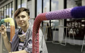 A person next to bike parks covered in knitting.