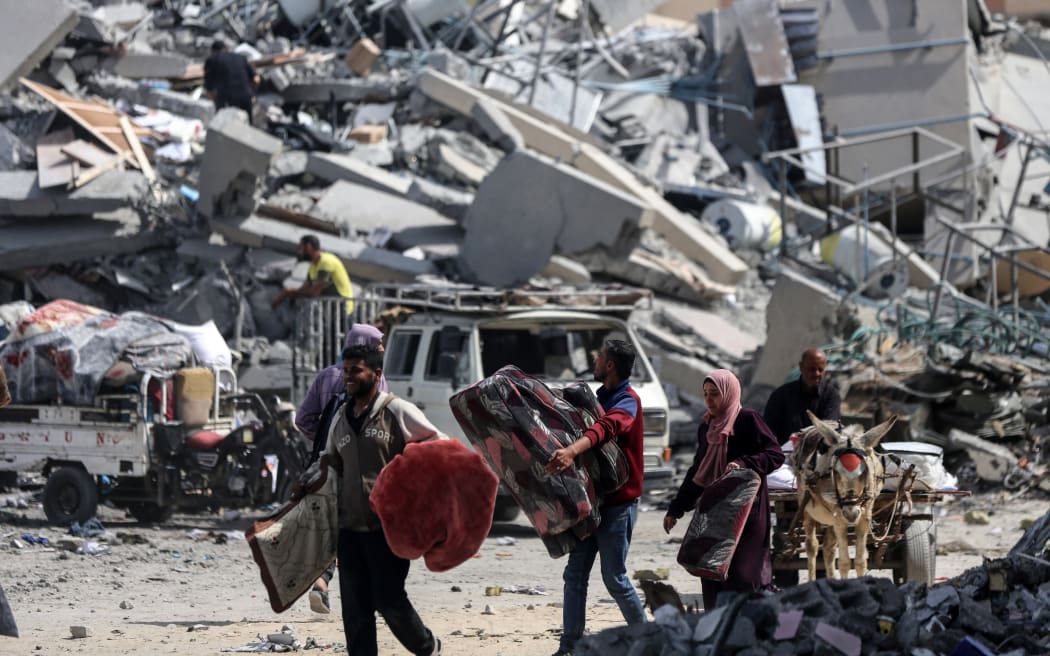 Palestinians walk past destroyed residential buildings in Qatari-funded Hamad City, following an Israeli raid in Khan Younis, southern Gaza Strip, 14 March 2024.