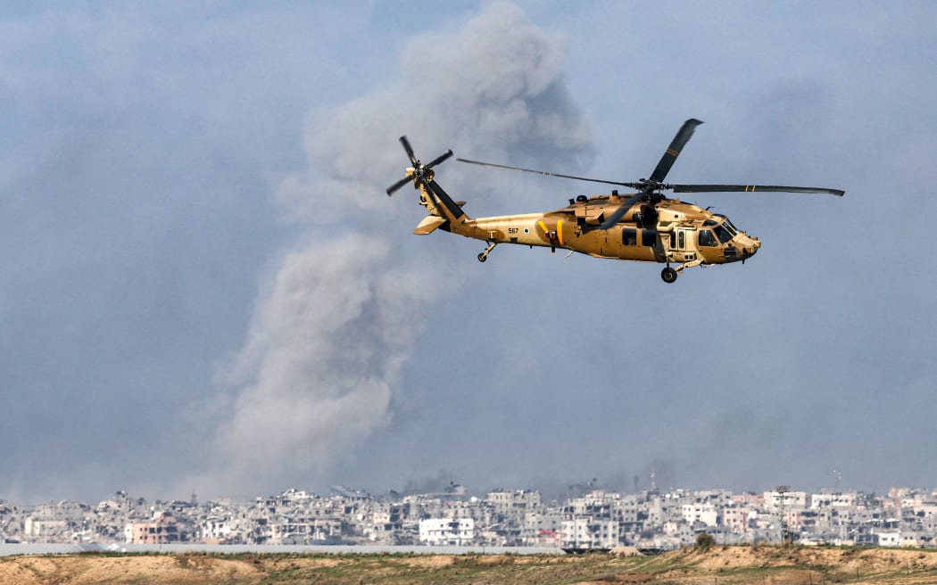 A picture taken from southern Israel near the border with the Gaza Strip on December 6, 2023, shows a Black Hawk military transport helicopter flying near the border with the Palestinian territory amid continuing battles between Israel and the militant group Hamas. Israeli forces were encircling southern Gaza's main city on Wednesday, battling Hamas militants through streets and buildings in some of the most intense combat of the two-month war.