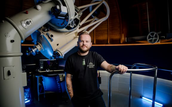Astronomy educator Josh Aoraki stands to the right a Stardome telescope.