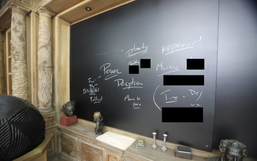 A chalkboard in one room is inscribed with words that include "deception", "power", "truth" and "political". Other words have been redacted.