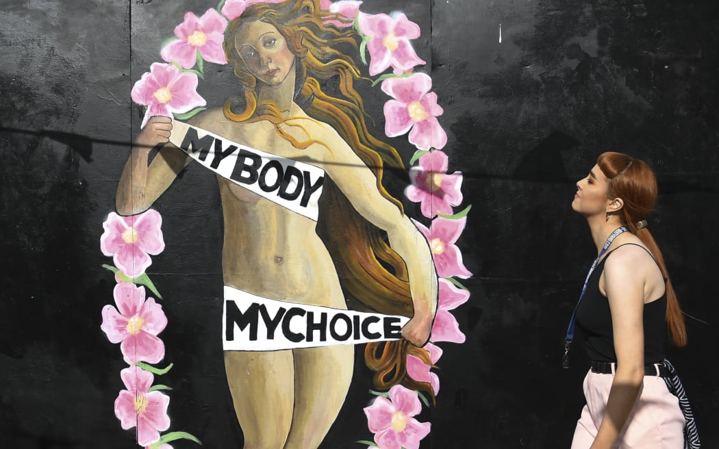 A woman walks in front of a pro-choice mural relating to the laws regarding abortion in Dublin