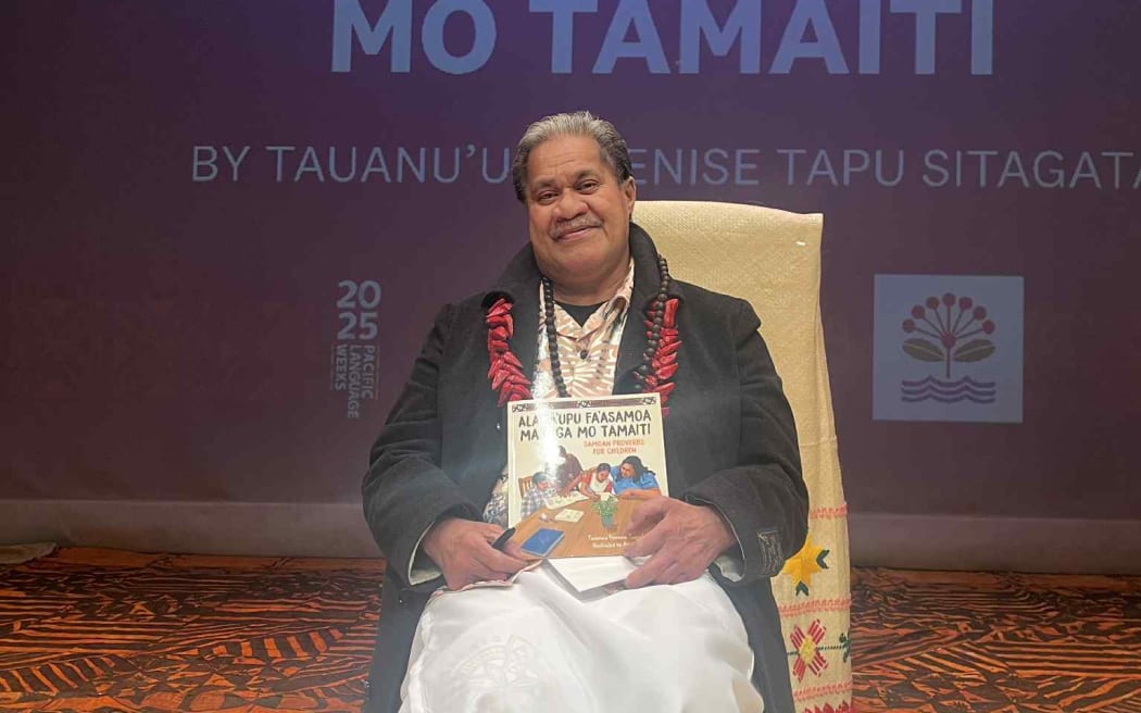 Tusitala (Author) Tauanu'u smiling in joy as he holds his newly published book - Samoan Proverbs for Children.