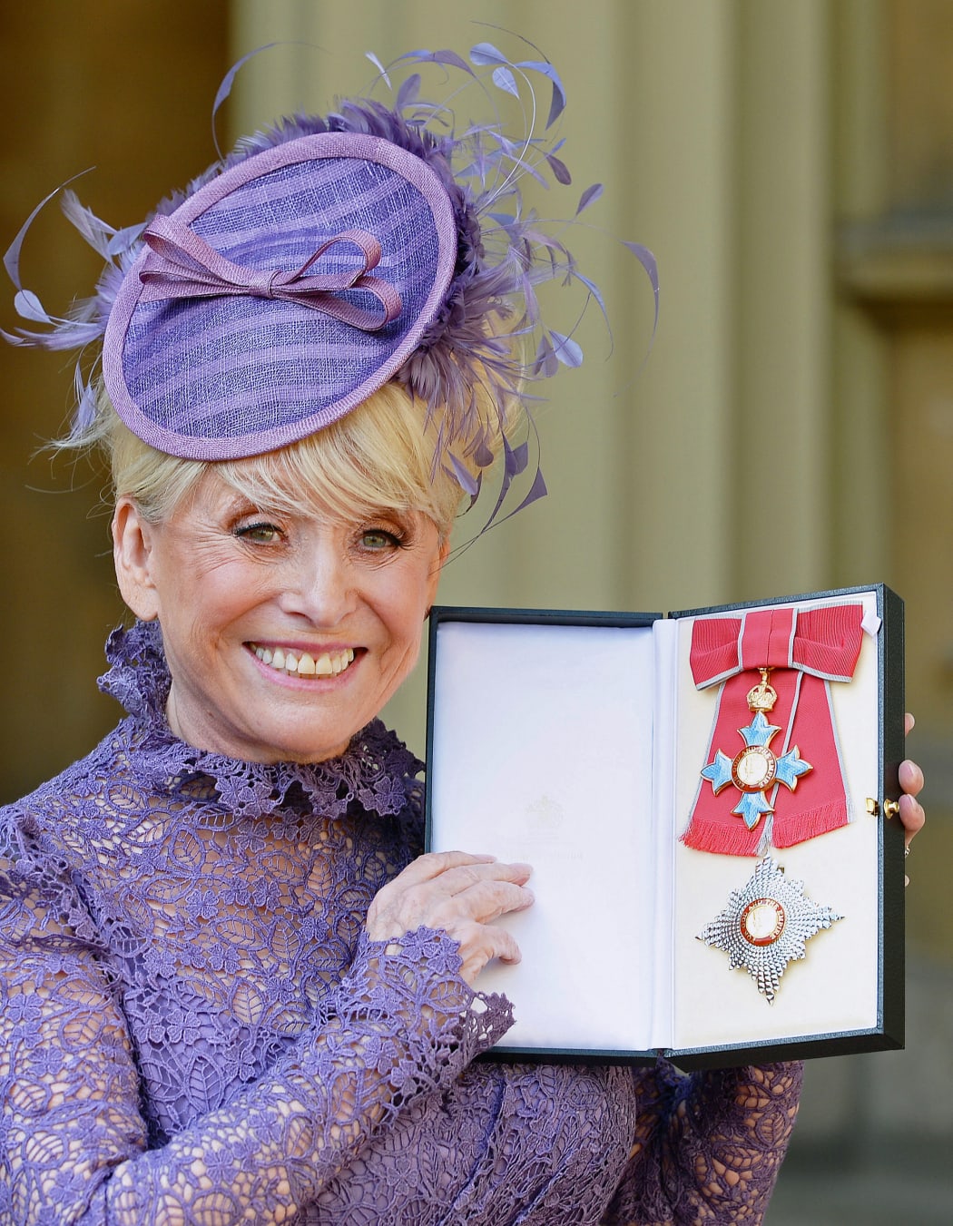 British actress Barbara Windsor poses with her insignia after being appointed a Dame Commander of the order of the British Empire (DBE) at an investiture ceremony at Buckingham Palace in London on March 22, 2016.