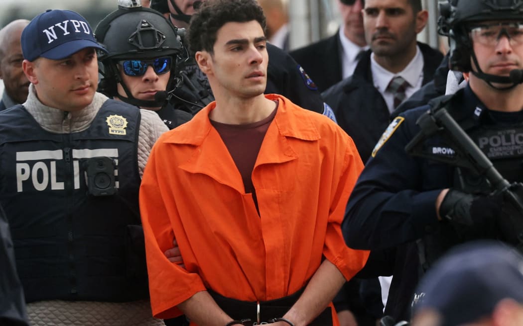 Luigi Mangione, suspect in the killing of UnitedHealthcare CEO Brian Thompson in New York City, arrives at a heliport with members of the NYPD on 19 December in New York City. The 26-year-old was arrested in Pennsylvania on December 9 after being spotted at a McDonald's in Altoona amid a national manhunt. Mangione also appeared in a Pennsylvania court on forgery and firearms charges today, where he waived extradition to New York after being indicted on 11 charges including first-degree murder in furtherance of terrorism.   Spencer Platt/Getty Images/AFP (Photo by SPENCER PLATT / GETTY IMAGES NORTH AMERICA / Getty Images via AFP)
