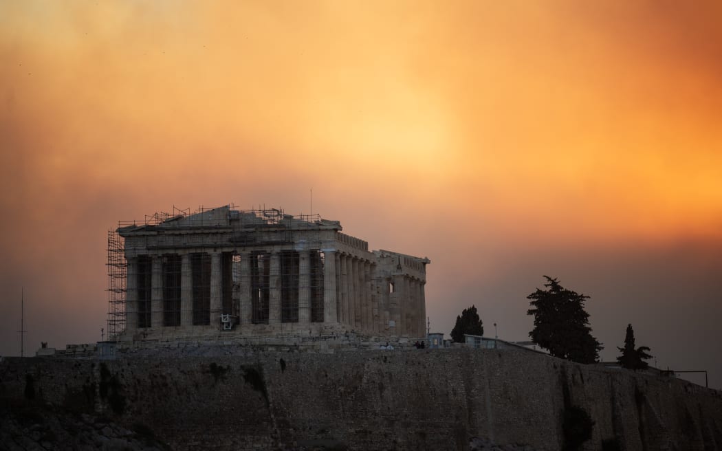 This photograph shows the Parthenon temple atop the Acropolis hill in a smoke cloud from a wildfire, in Athens on August 12, 2024. On August 12, 2024, Greece's civil protection authorities ordered the evacuation of several towns in the north-eastern suburbs of Athens, threatened by a violent fire that started the day before and is spreading. (Photo by Angelos TZORTZINIS / AFP)