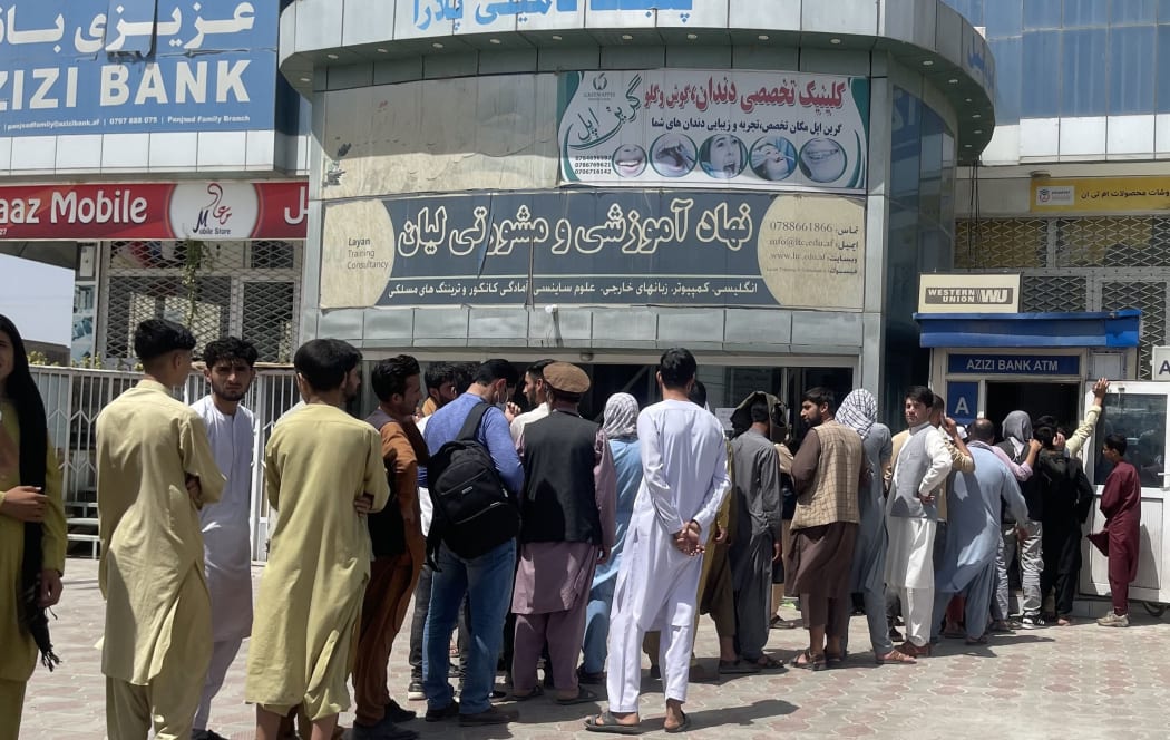 KABUL, AFGHANISTAN 15: Afghan people line up outside AZIZI Bank to take out cash as the Bank suffers amid money crises in Kabul, Afghanistan, on August 15, 2021.