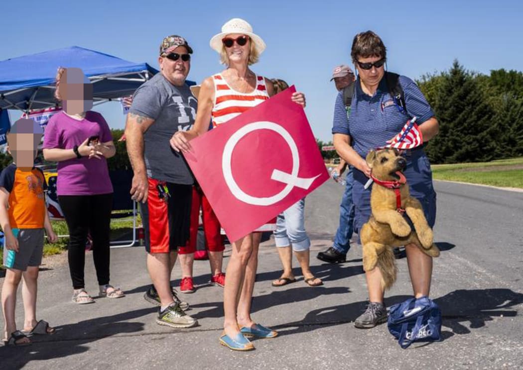 MANKATO, MN - AUGUST 17: Kim Harty (C) holds a Q Anon sign outside Mankato Regional Airport.