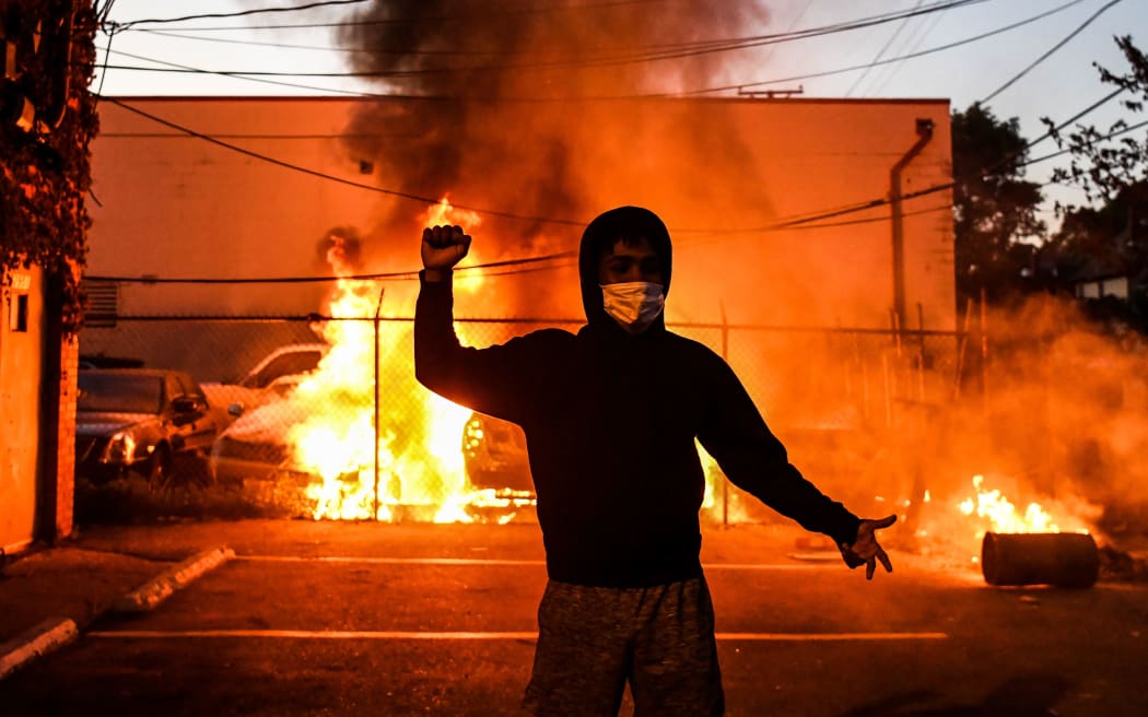 A protestor gestures as cars burn behind him during a demonstration in Minneapolis, Minnesota, on May 29, 2020 over the death of George Floyd, a black man who died after a white policeman kneeled on his neck for several minutes.