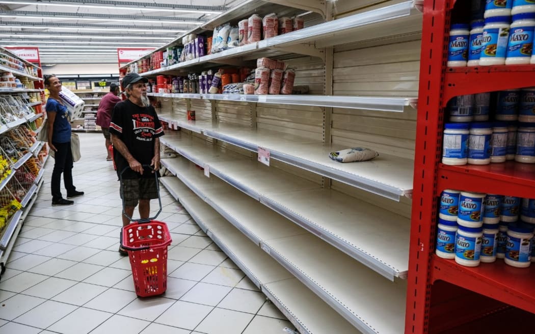 People look for groceries and food among nearly empty shelves in a supermarket in the Magenta district of Noumea, France's Pacific territory of New Caledonia, on May 18, 2024. Anger over France's plan to impose new voting rules has spiralled into the deadliest violence in four decades in the archipelago of 270,000 people, which lies between Australia and Fiji -- 17,000 kilometres (10,600 miles) from Paris. (Photo by Theo Rouby / AFP)