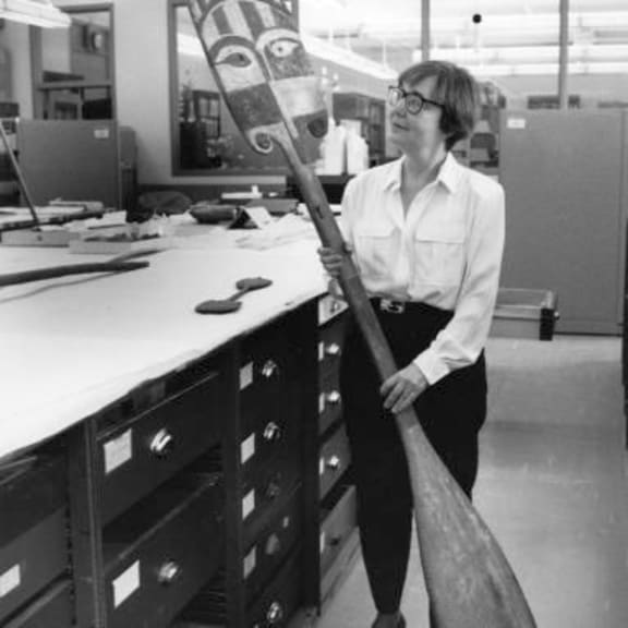 Adrienne Kaeppler holding a paddle at Smithsonian Museum.