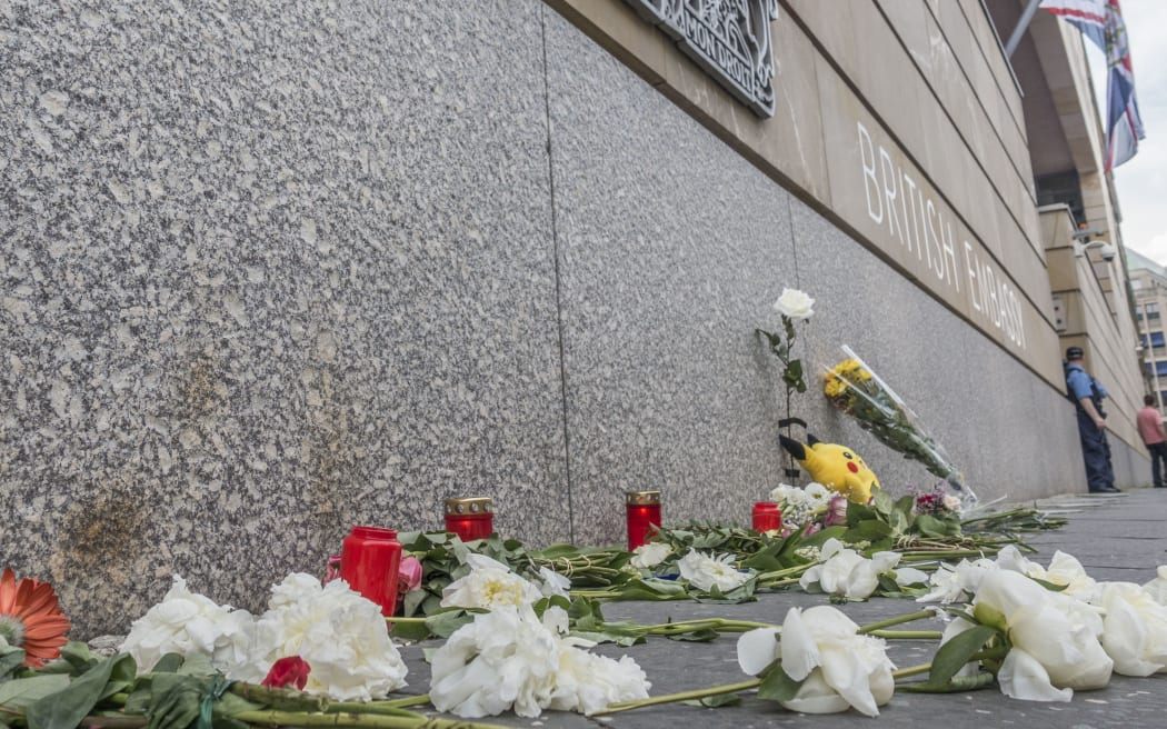 Flowers and candles are seen laid on the wall of the British Embassy in Berlin