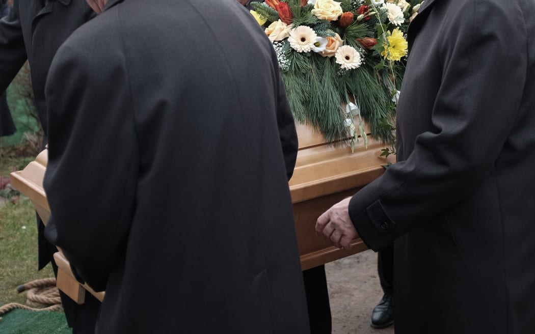 Pallbearers carry a coffin decorated with flowers