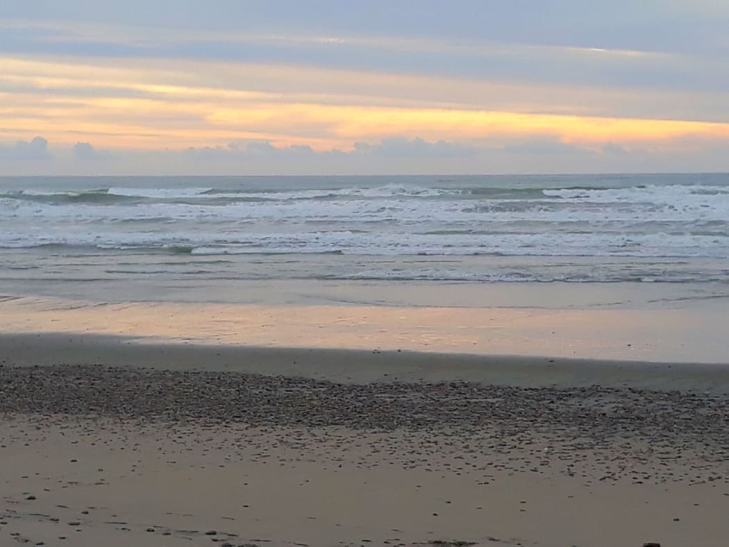 Storm clouds start to gather as the sun sets over Karamea Beach
