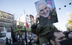 An Iranian boy holds a portrait of former commander of the Islamic Revolutionary Guard Corps General Qasem Soleimani during a funeral for unknown martyrs of the Iran-Iraq war (1980-88) in downtown Tehran, on Thursday.