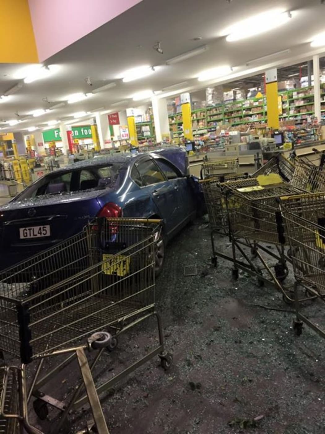 The car went through the supermarket window.