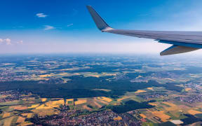 Airplane windows view above the earth on landmark down. View from an airplane window over a wing flying high above farmlands and fields.