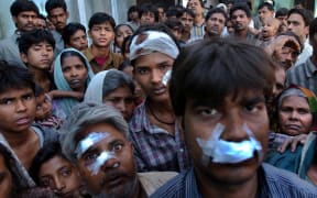 Muslims who had begged police to protect them the day before sit huddled in the wreckage of their burned out homes after a mob of Hindu neighbors.