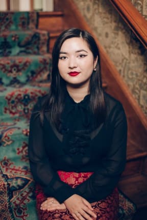 RNZ Concert presenter Cadence Chung standing in front of a flight of stairs.