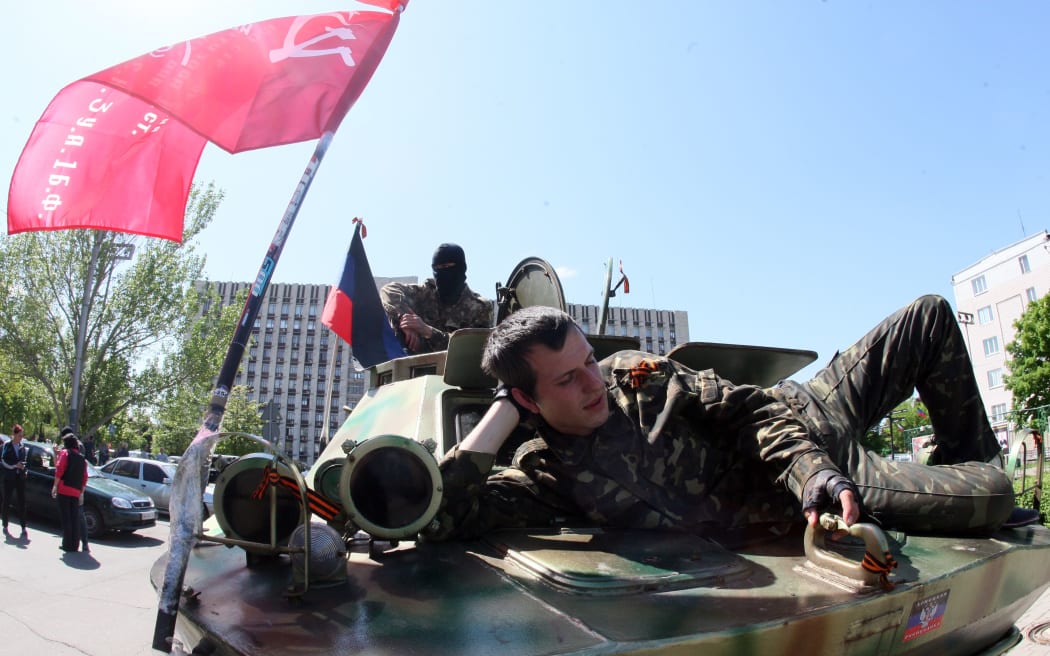 A pro-Russian separatist resting on an armoured vehicle parked outside a regional state building in Donetsk on the eve of the referendum.