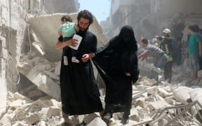 A family walks amid the rubble of destroyed buildings following a reported air strike on the rebel-held neighbourhood of al-Kalasa in the northern Syrian city of Aleppo, on April 28, 2016.