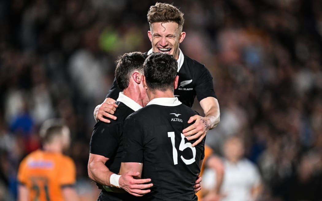 Cam Roigard celebrates his try with Damian McKenzie and Will Jordan.