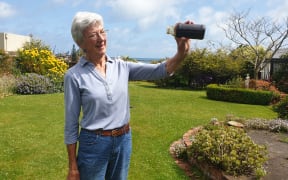 Daveena Dawrant, from New Plymouth, holds a jar of oil, which was collected from an abandoned well underneath her backyard.