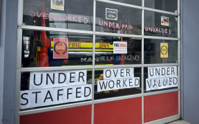 The windows of the Auckland city fire station. They are covered in protest slogans: 'UNDER STAFFED - OVER WORKED - UNDER VALUED'.