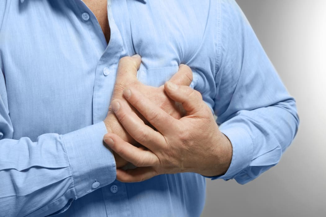 Elderly man holding hands on chest suffering from heart attack, closeup