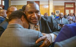 James Marape (right) is hugged by a supporter.