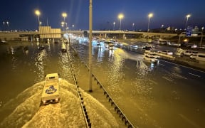 Vehicles drive on flooded streets following heavy rains in Dubai on April 17, 2024. Dubai, the Middle East's financial centre, has been paralysed by the torrential rain that caused floods across the UAE and Bahrain and left 18 dead in Oman on April 14 and 15. (Photo by Giuseppe CACACE / AFP)