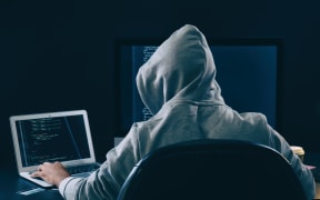 Man wearing hoodie hacking server in dark room