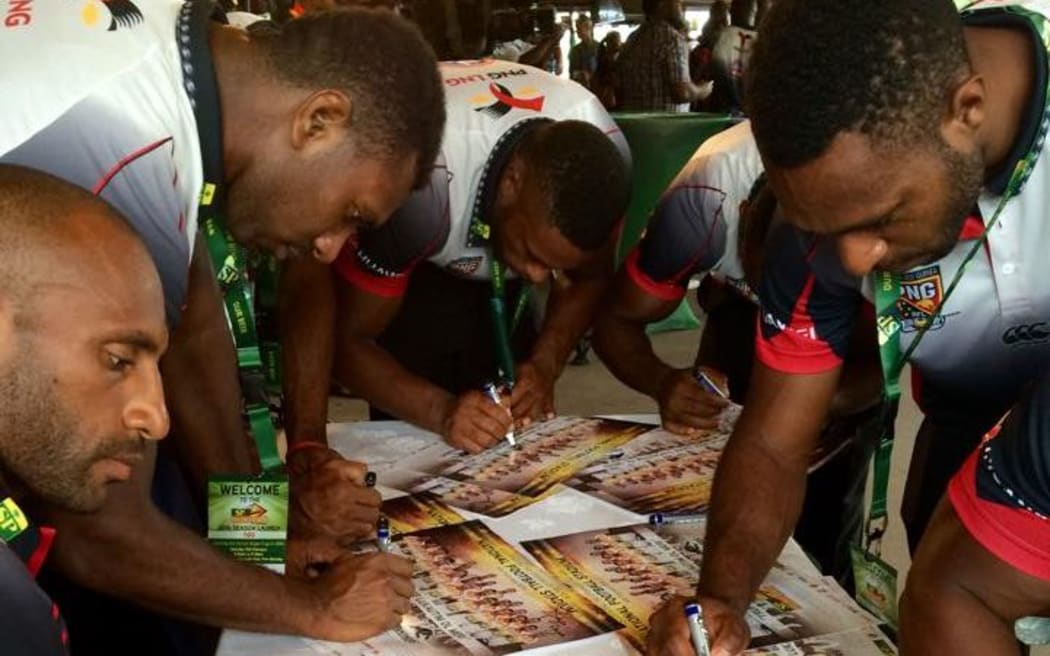 PNG Hunters players sign posters at their 2016 season launch.