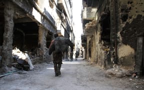 Men walk past destroyed buildings in the Yarmuk Palestinian refugee camp in the Syrian capital Damascus on April 6, 2015.