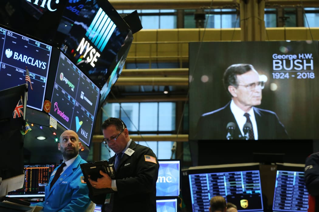 Traders work on the floor of the New York Stock Exchange (NYSE) as a picture of former President George H.W. Bush appears on a screen.
