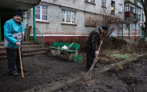 Residents clean the entrance of their building following a Russian missile strike in the city of Kramatorsk, eastern Ukraine on December 23, 2022.