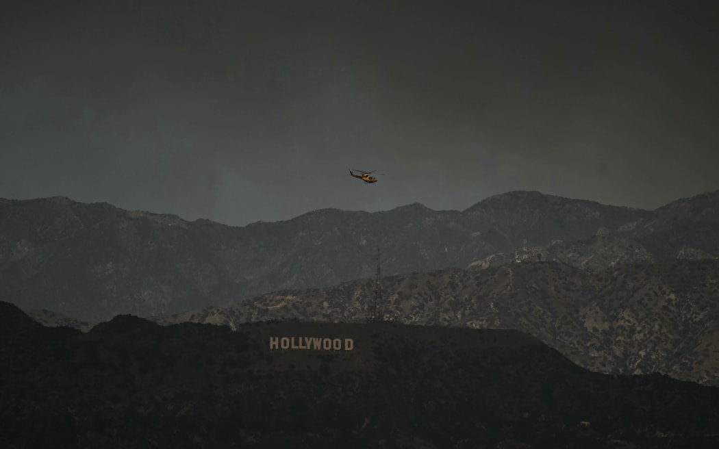 A firefighting helicopter flies above the hollywood sign as the sky is engulfed in dark smoke from the many fires burning around the city, as seen from Kenneth Hahn State Recreation Area in Los Angeles, on January 8, 2025. - Rampaging wildfires around Los Angeles have killed at least two people, officials said January 8 as terrifying blazes leveled whole streets, torching cars and houses in minutes.
More than 1,000 buildings have burned in multiple wildfires that have erupted around America's second biggest city, forcing tens of thousands of people from their homes. (Photo by Patrick T. Fallon / AFP)