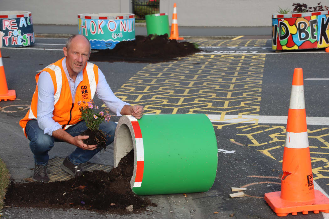 en7Streets.Jpg Up
turned...Gore District 
Council roading manager 
Peter Standring rescues 
plants that were buried in 
soil when a planter pot 
was overturned on the 
corner of Ardwick and 
Preston streets on 
Monday night.