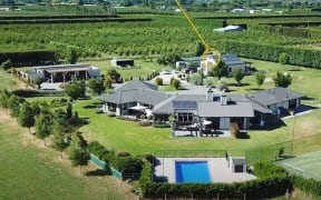Wayne and Lynn Simpson's home in Pakowhai, pictured before the flood brought by Cyclone Gabrielle, with a circle showing the tip of roof that remained above the water where the couple and guests waited for rescue.