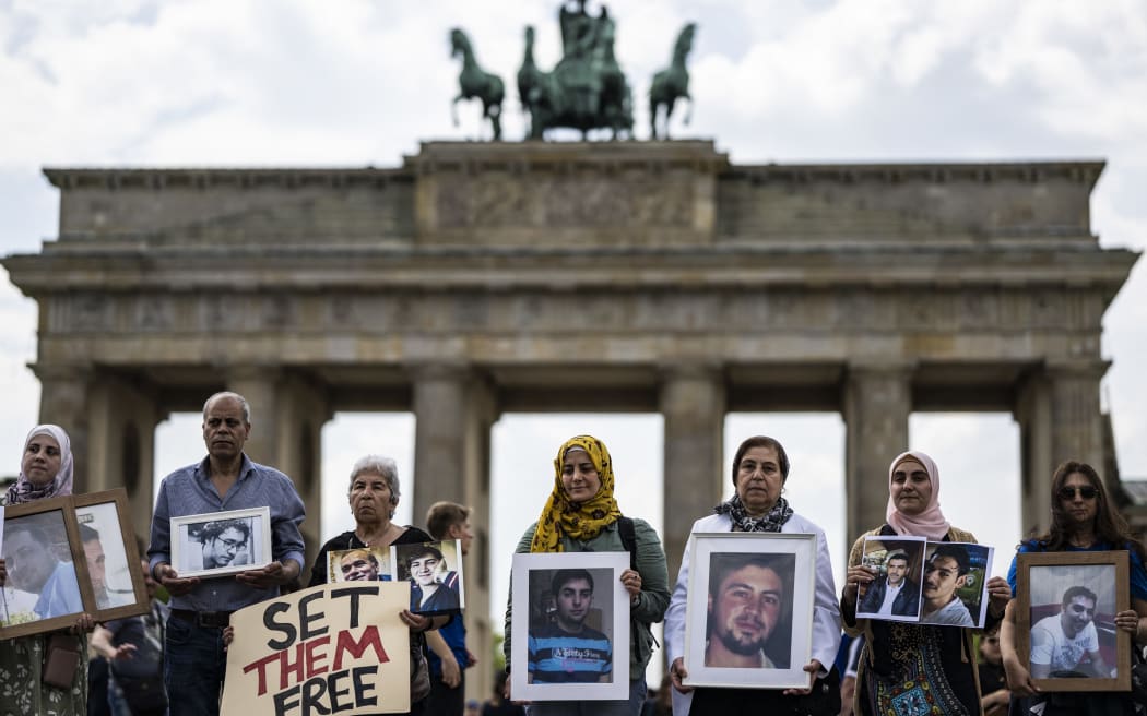 Activists and relatives of Syrians suspected of being detained or missing pose with their portraits during a demonstration in front of Berlin's Brandenburg gate on 7 May, 2022.