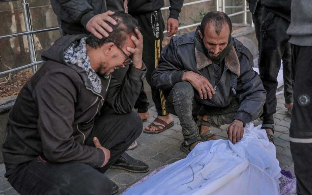 EDITORS NOTE: Graphic content / People mourn at Al-Shifa hospital in Gaza City, over the body of a Palestinian killed in an early morning incident when residents rushed toward aid trucks in Gaza City on February 29, 2024. The health ministry in Hamas-run Gaza said Israeli forces shot dead dozens of people when a crowd rushed towards aid trucks on February 29. Israeli sources confirmed that troops opened fire at Palestinians, with one saying soldiers thought they "posed a threat", and that many died when they were run over by aid trucks.