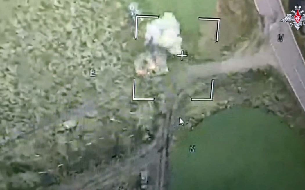 An image taken from a handout footage released by the Russian Defence Ministry on August 6, 2024, shows a Russian drone attack on Ukrainian armoured vehicles outside the town of Sudzha, Kursk Region.