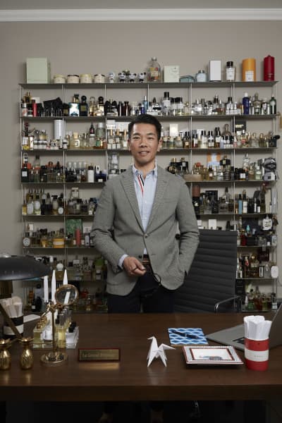 Christopher Yu standing with shelves behind him showcasing a massive collection of fragrances and candles.