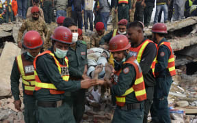 Pakistani rescuers move a man rescued from under the rubble of the collapsed factory.